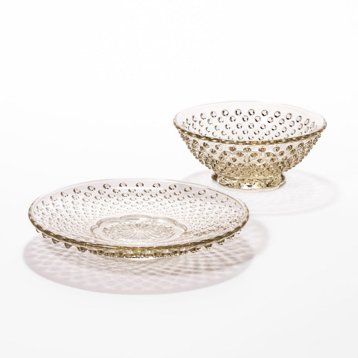 Amber-toned glass dessert bowl and saucer set with raised dot pattern and starburst base, ideal for refined sweets or fruit servings.
