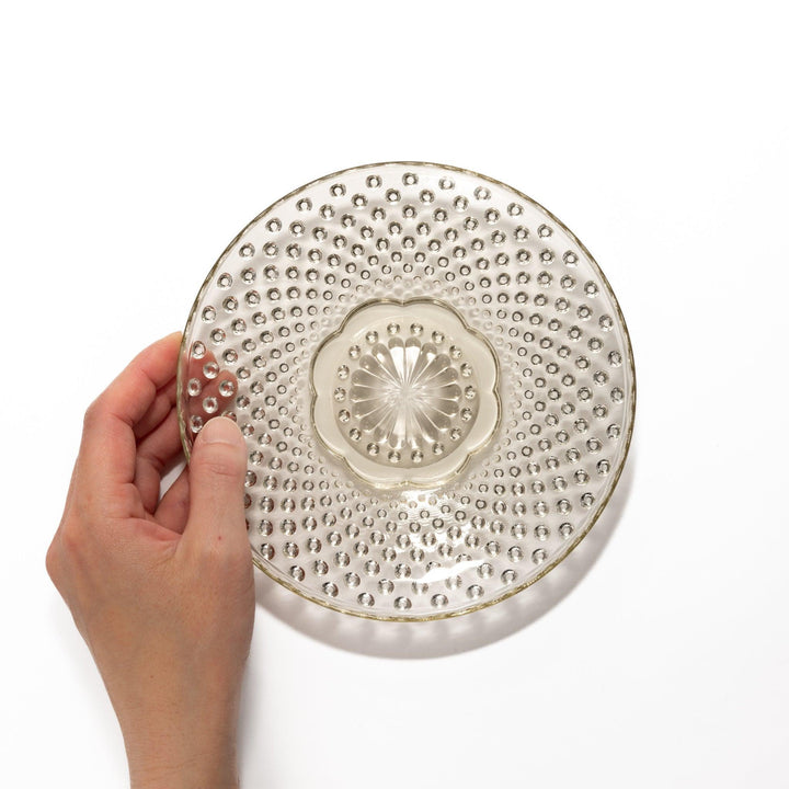 Amber-toned glass dessert bowl and saucer set with raised dot pattern and starburst base, ideal for refined sweets or fruit servings.