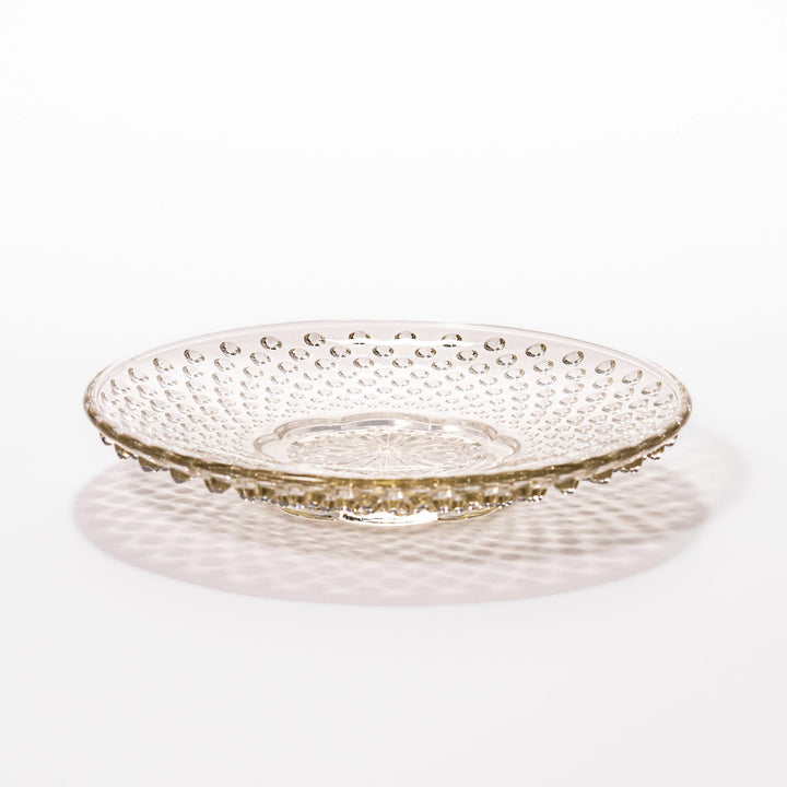 Amber-toned glass dessert bowl and saucer set with raised dot pattern and starburst base, ideal for refined sweets or fruit servings.