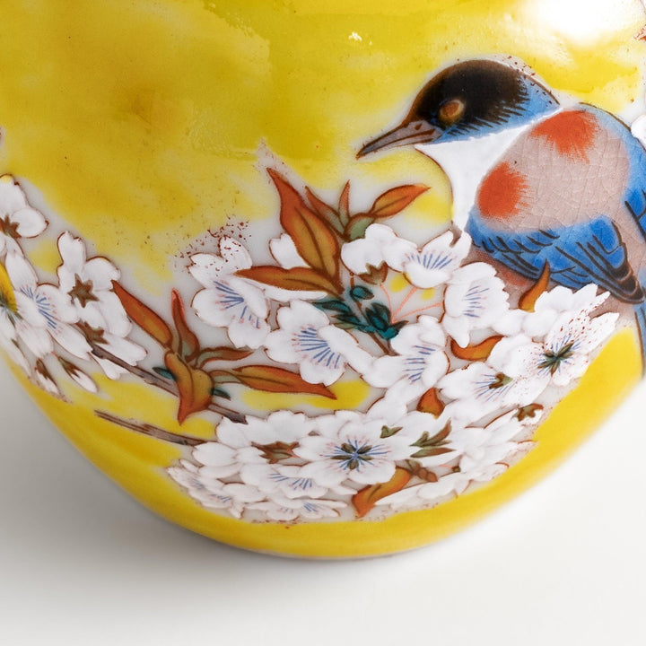 Bright yellow vase adorned with delicate cherry blossoms and a colorful bird, capturing the essence of spring in a beautifully painted design.