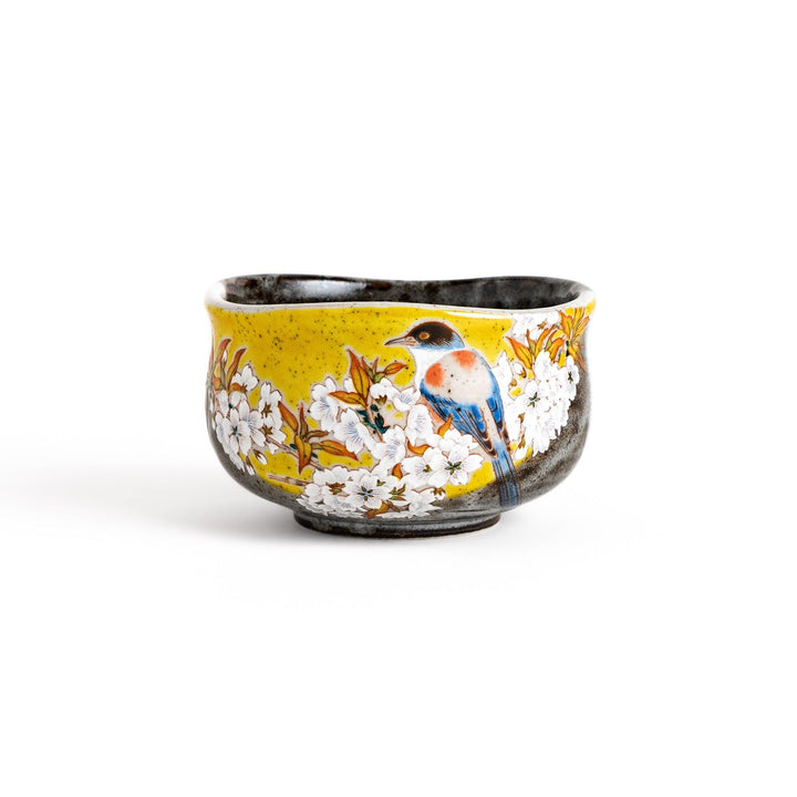 Yellow matcha bowl with a beautiful bird perched on a flowering branch, perfect for preparing and enjoying a delicious bowl of matcha.