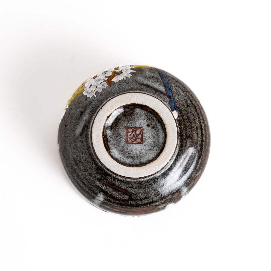 Yellow matcha bowl with a beautiful bird perched on a flowering branch, perfect for preparing and enjoying a delicious bowl of matcha.