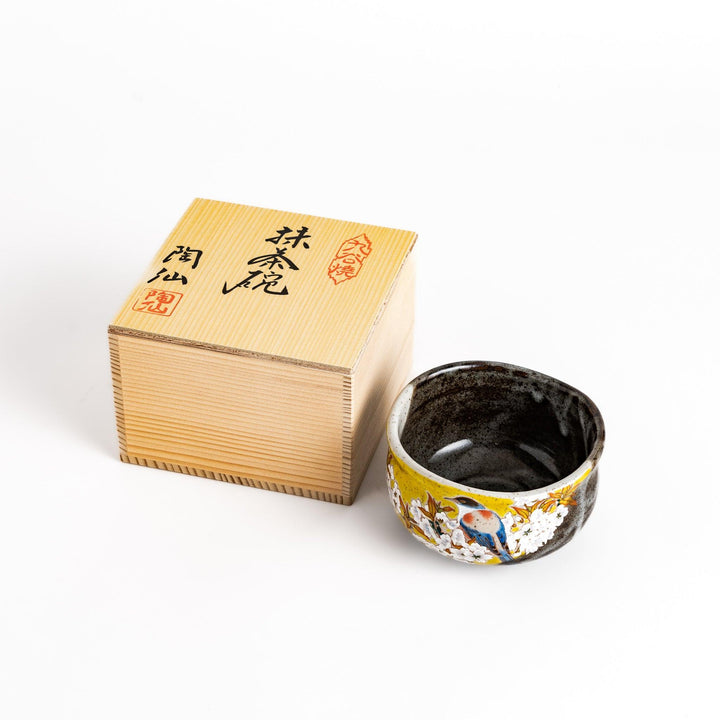 Yellow matcha bowl with a vibrant bird and flower design, nestled in a traditional wooden box, perfect for a unique tea ceremony experience.