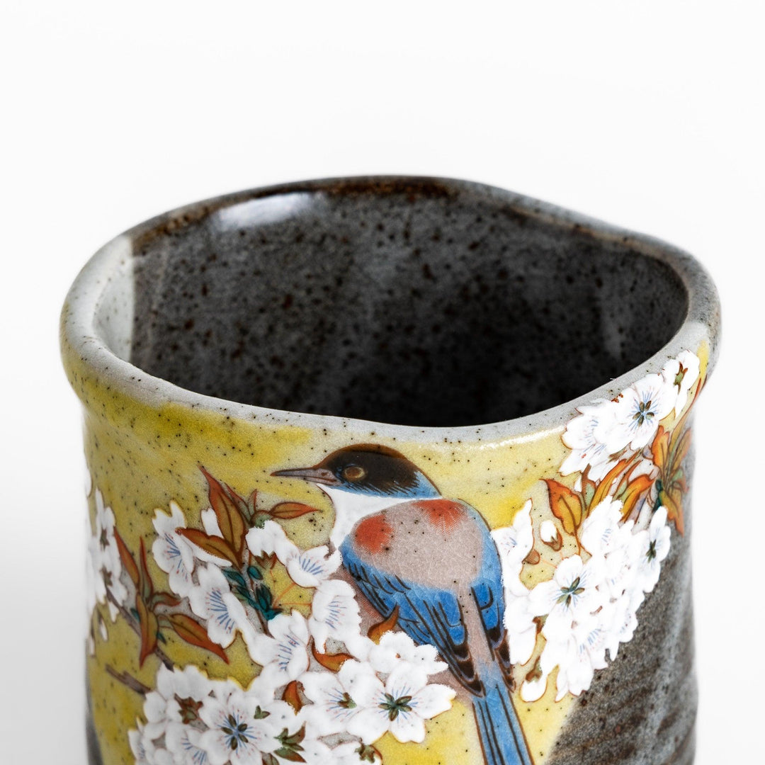 Tea Cup featuring a bird perched on blooming sakura flowers, set against a yellow and gray background.