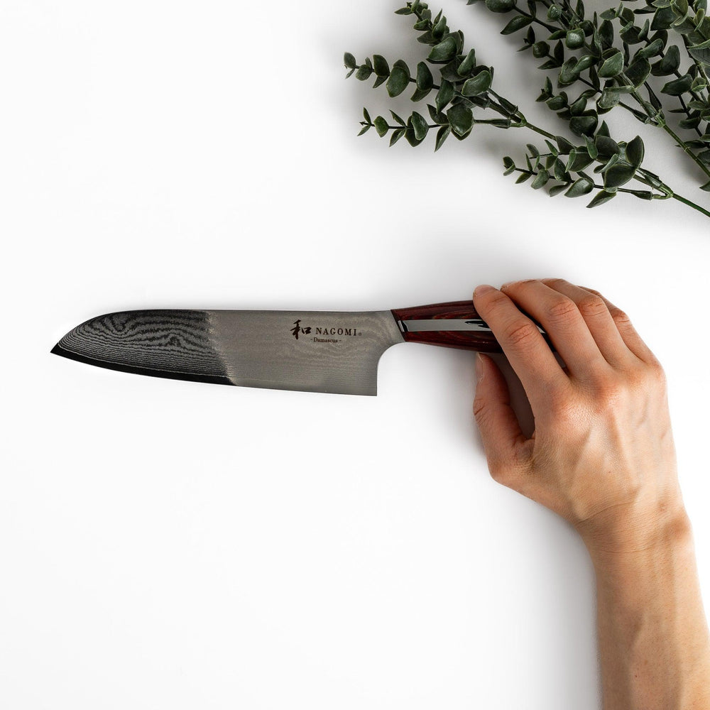 A high-quality Nagomi Damascus Santoku knife featuring a beautifully patterned blade and a striped wooden handle, offering both elegance and precision for all your culinary needs.
