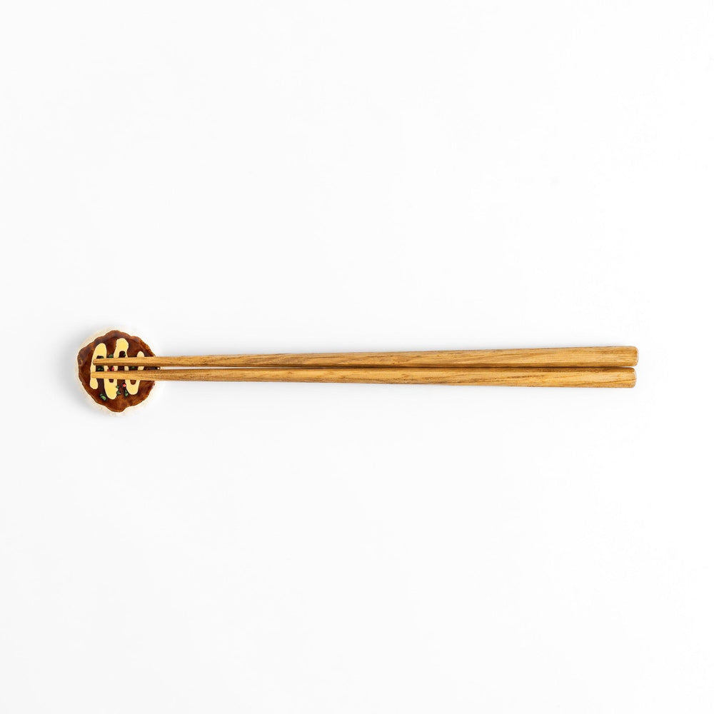 Fun Okonomiyaki-shaped chopstick rest with realistic details, including drizzled sauce and colorful toppings.