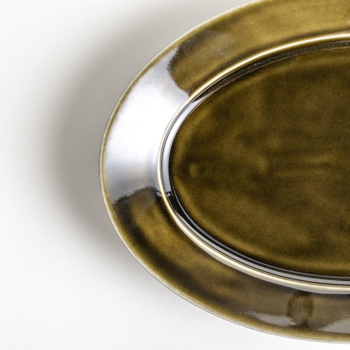 Sleek, dark brown or olive colored oval dinner plate with a glossy finish, simple and minimalist.