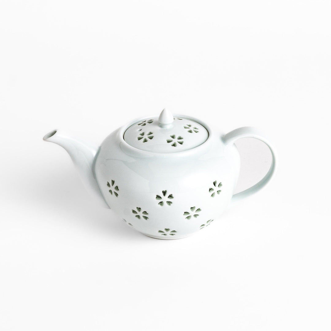 Elegant teapot with delicate petal-shaped cutouts, creating a soft glow through the porcelain, complemented by a pointed lid and smooth handle for a refined tea experience.