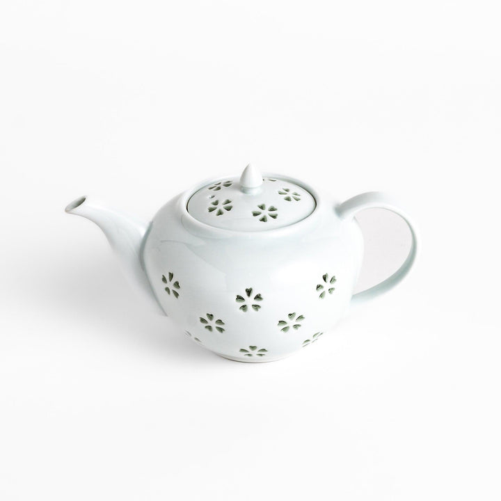 Elegant teapot with delicate petal-shaped cutouts, creating a soft glow through the porcelain, complemented by a pointed lid and smooth handle for a refined tea experience.