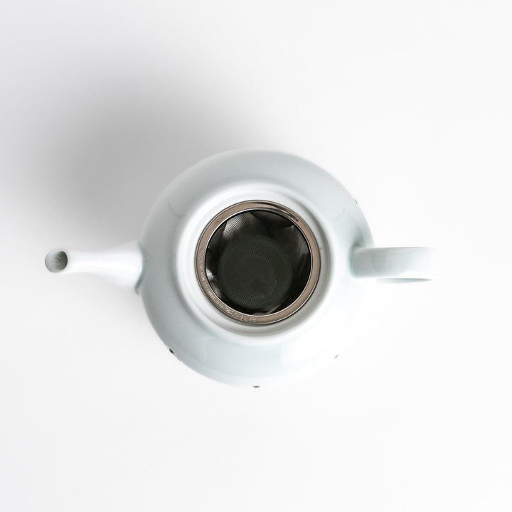 Elegant teapot with delicate petal-shaped cutouts, creating a soft glow through the porcelain, complemented by a pointed lid and smooth handle for a refined tea experience.