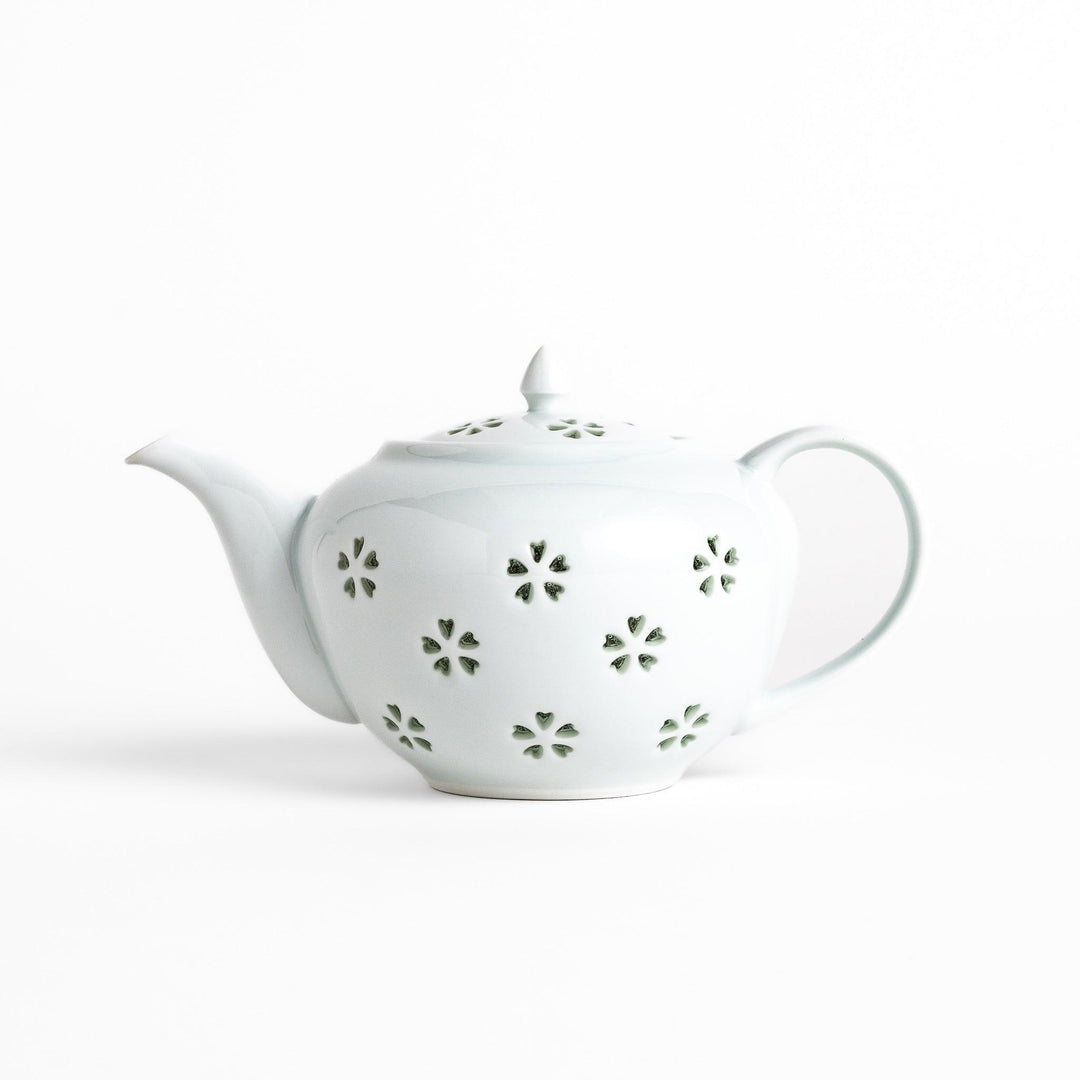Elegant teapot with delicate petal-shaped cutouts, creating a soft glow through the porcelain, complemented by a pointed lid and smooth handle for a refined tea experience.