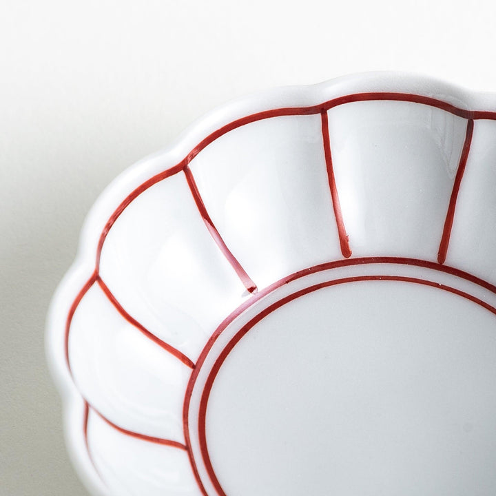 A small white porcelain condiment bowl with delicate blue or red lines radiating from the center, creating a simple yet elegant design.