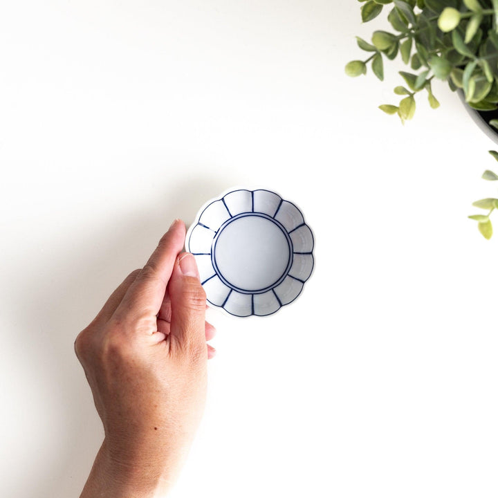 A small white porcelain condiment bowl with delicate blue or red lines radiating from the center, creating a simple yet elegant design.