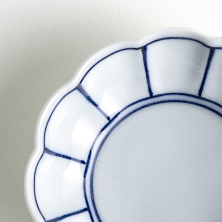A small white porcelain condiment bowl with delicate blue or red lines radiating from the center, creating a simple yet elegant design.