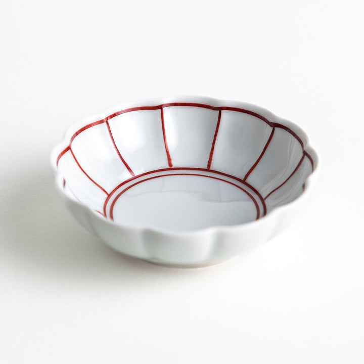 A small white porcelain condiment bowl with delicate blue or red lines radiating from the center, creating a simple yet elegant design.