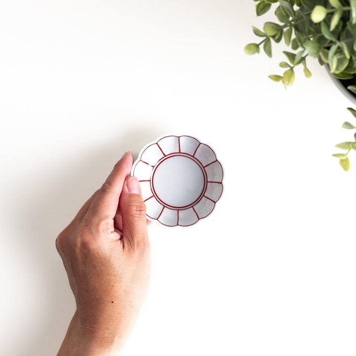 A small white porcelain condiment bowl with delicate blue or red lines radiating from the center, creating a simple yet elegant design.
