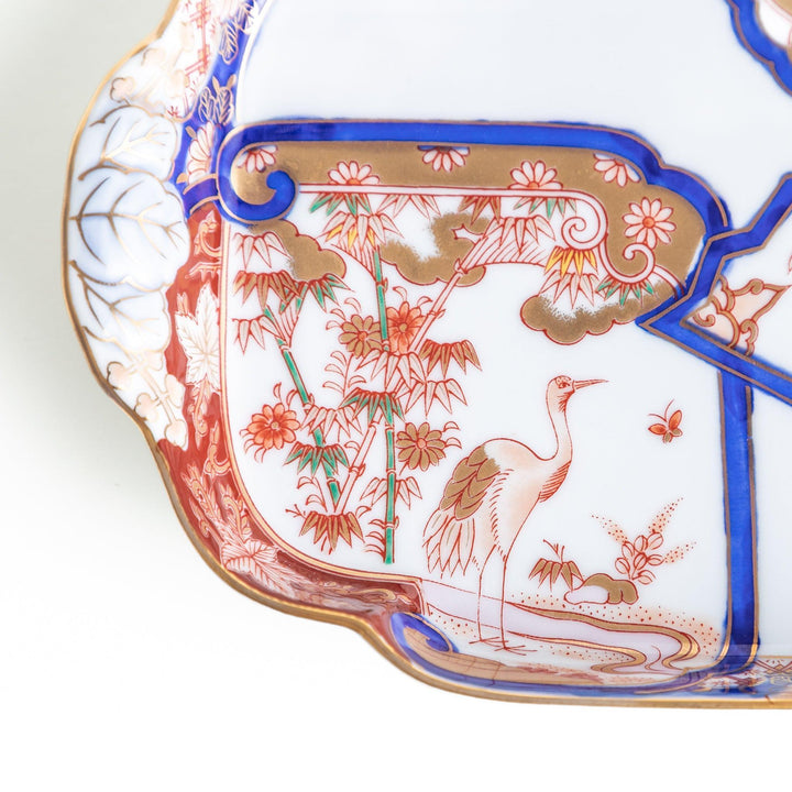 A rectangular salad plate with handles, decorated with scenes of cranes and trees in a traditional Japanese style, bordered by intricate red, blue, and gold patterns.