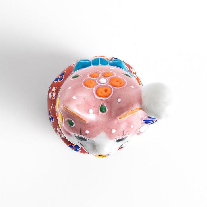 Charming pink blossom Maneki Neko figurine, adorned with colorful floral patterns and a golden bell, symbolizing good luck and prosperity with a cheerful waving gesture.