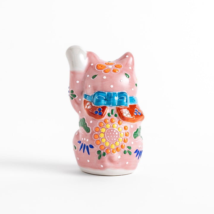 Charming pink blossom Maneki Neko figurine, adorned with colorful floral patterns and a golden bell, symbolizing good luck and prosperity with a cheerful waving gesture.
