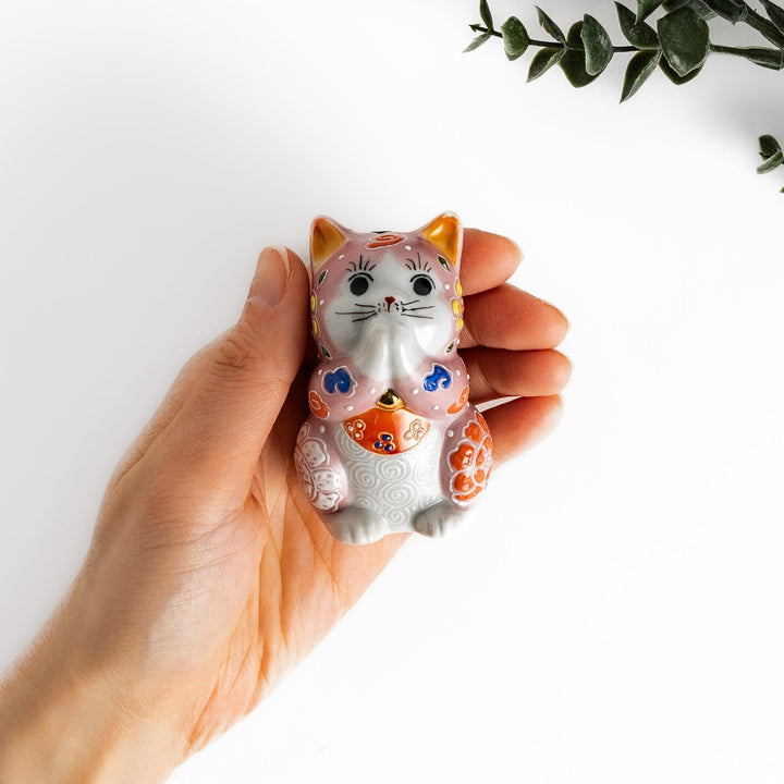 Maneki Neko figurine featuring a pink blossom design with vibrant colors and a praying posture for good fortune.