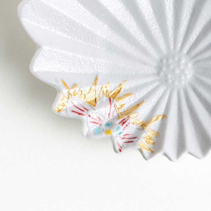 A white, leaf-shaped ceramic plate with delicate pink and gold floral decorations.