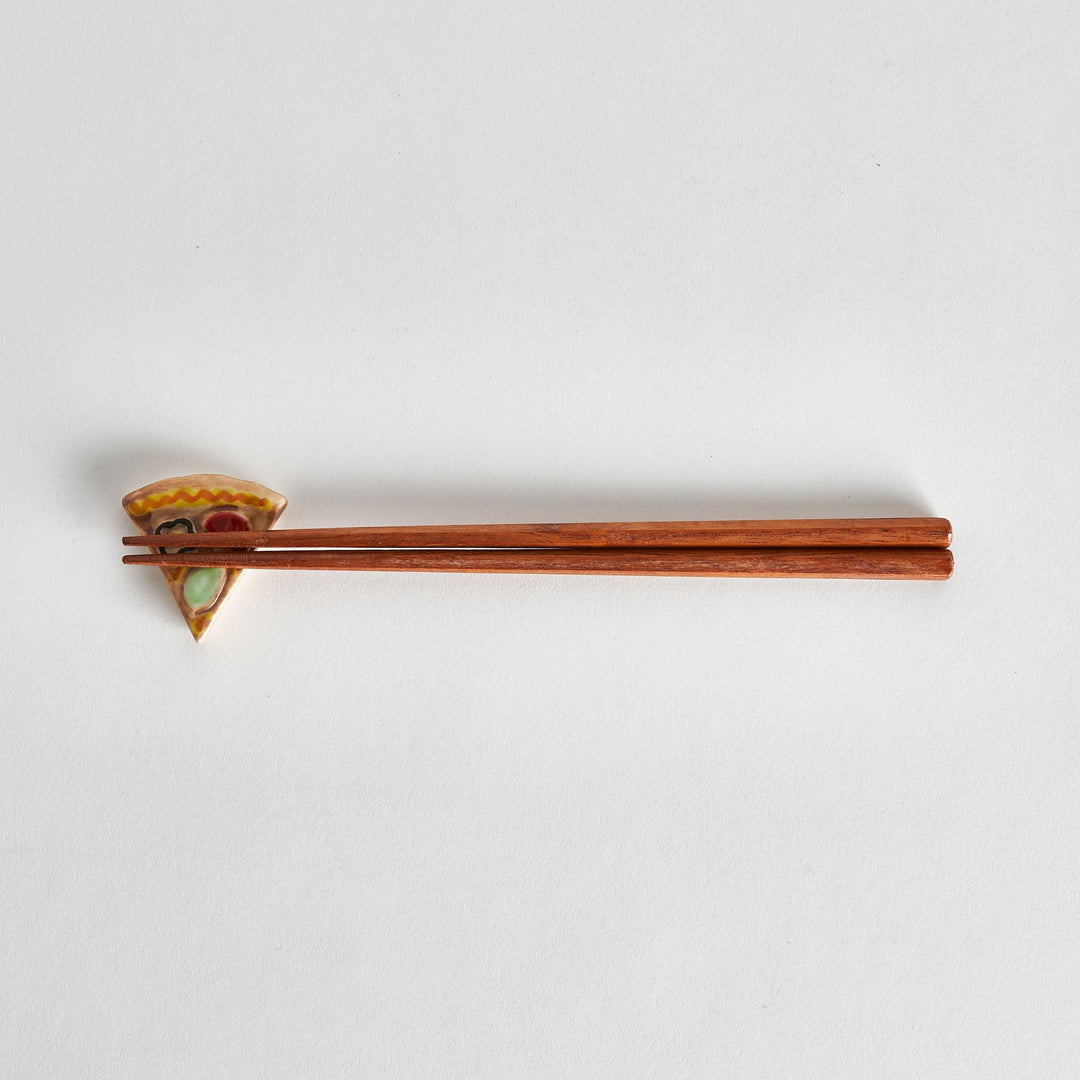 Full view of pizza chopstick rest with chopsticks placed on top, highlighting the playful pizza shape.