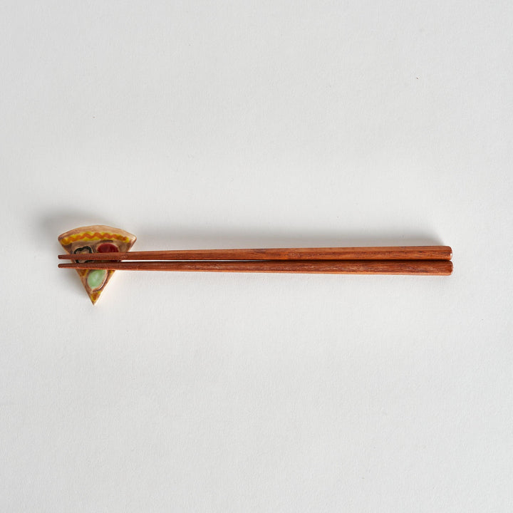 Full view of pizza chopstick rest with chopsticks placed on top, highlighting the playful pizza shape.