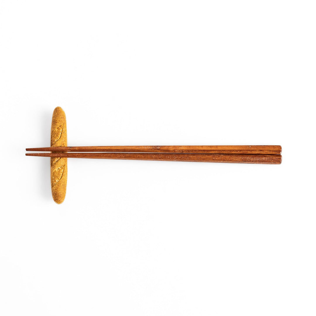 Plain baguette-shaped chopstick rest with a simple, elegant design, featuring detailed imprints resembling the crust of a baguette.