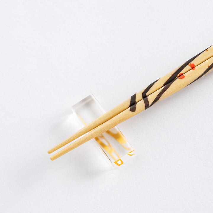 Chopsticks set in a wooden gift box with a blue interior. Red and green painted patterns on the chopsticks highlight Japanese artistry.