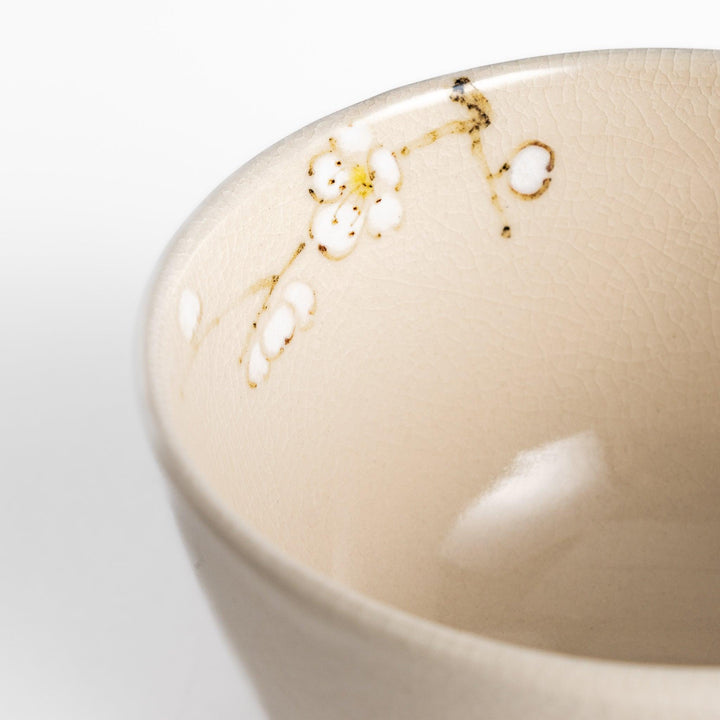 Plum Blossom Matcha Bowl with delicate pink floral designs on a cream-colored surface, perfect for enjoying matcha with a touch of elegance.