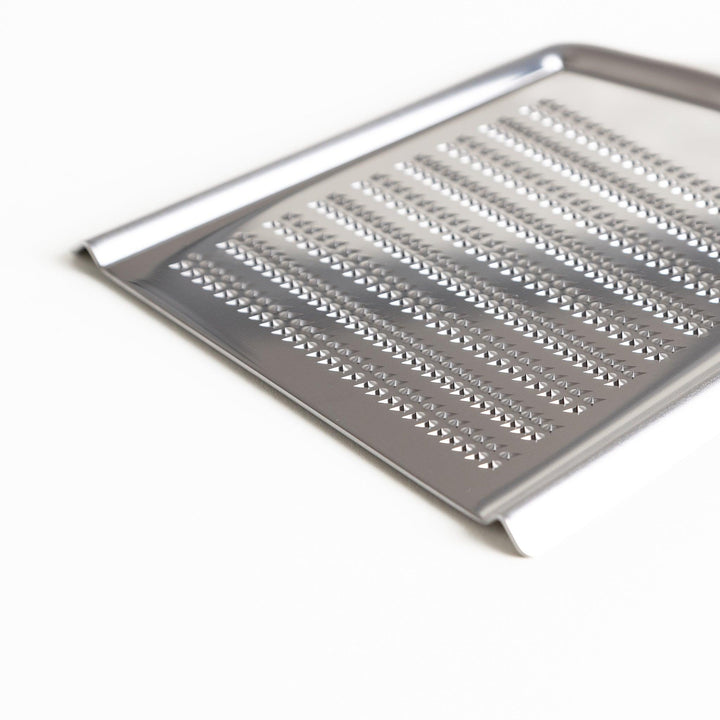 Durable stainless steel grater with sharp blades on both sides, a versatile kitchenware tool for efficiently grating vegetables, cheese, and other ingredients.