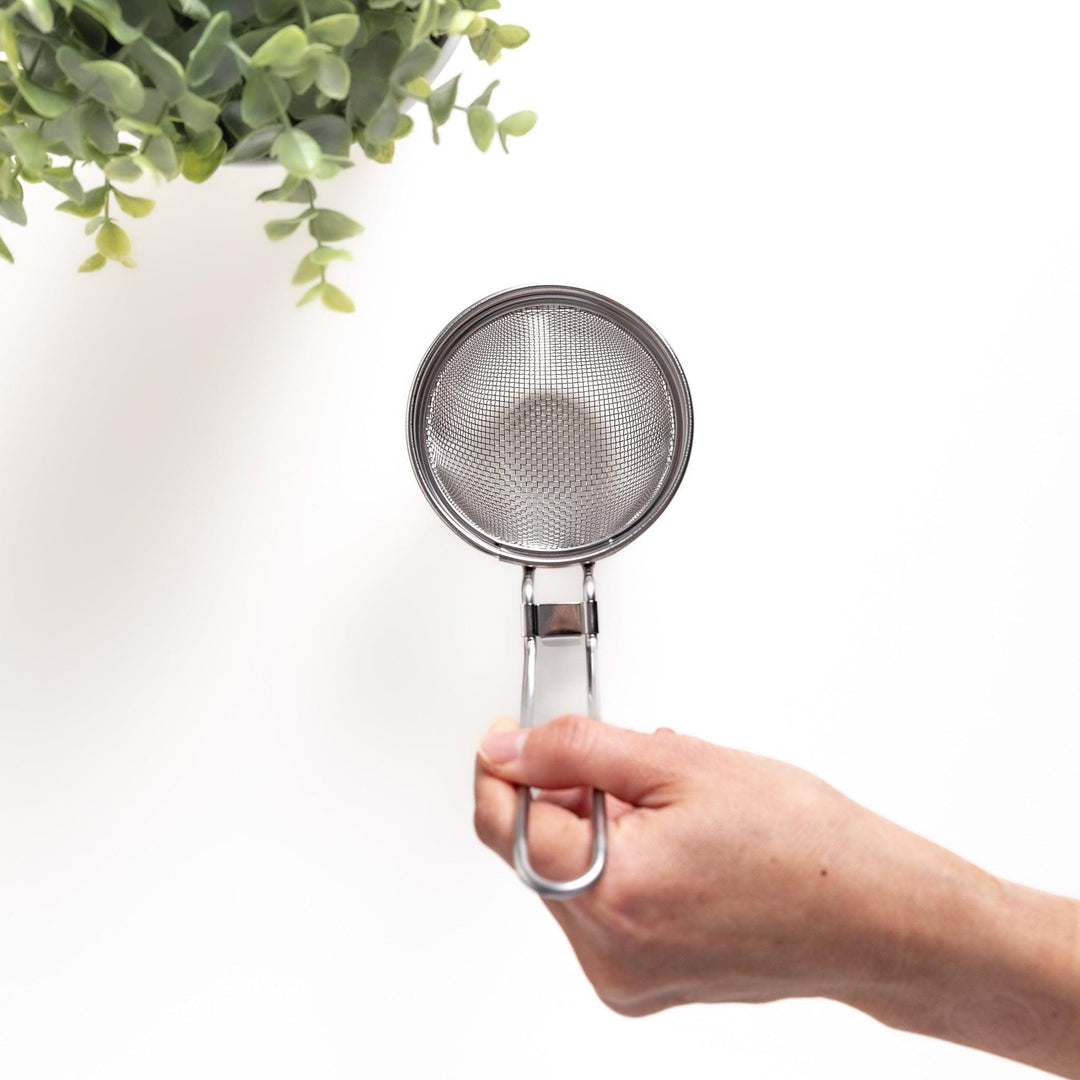 Hand holding a stainless steel miso strainer with a fine mesh and a sturdy handle, an essential kitchenware tool for preparing smooth and delicious miso soup.