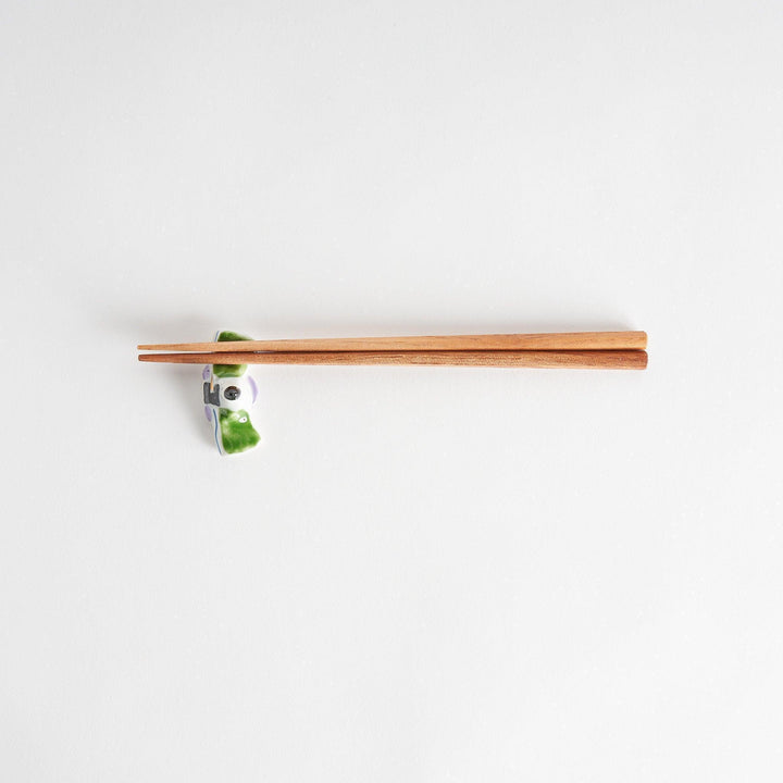 A ceramic chopstick rest shaped like a Japanese prince, painted in orange with floral accents.