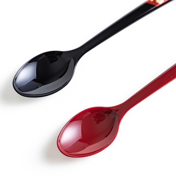 A set of two coffee spoons, one red and one black, with gold floral designs on the handles.