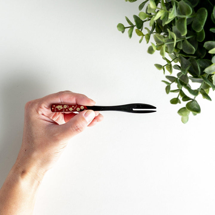 A set of two dessert forks, one red and one black, with rabbit designs on the handles.