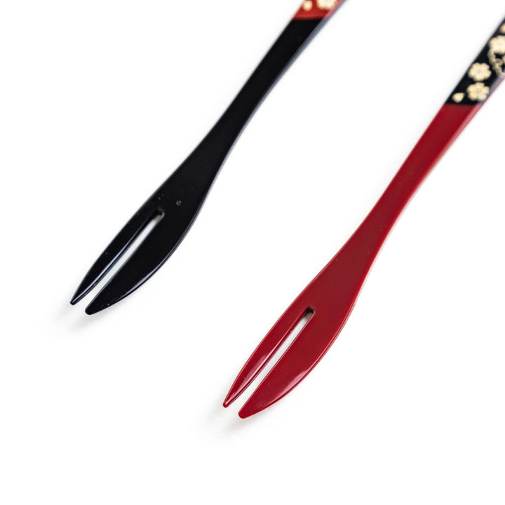 A set of two dessert forks, one red and one black, with rabbit designs on the handles.