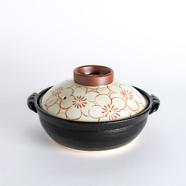 A 8-inch donabe with a vibrant red blossom pattern lid and black pot.