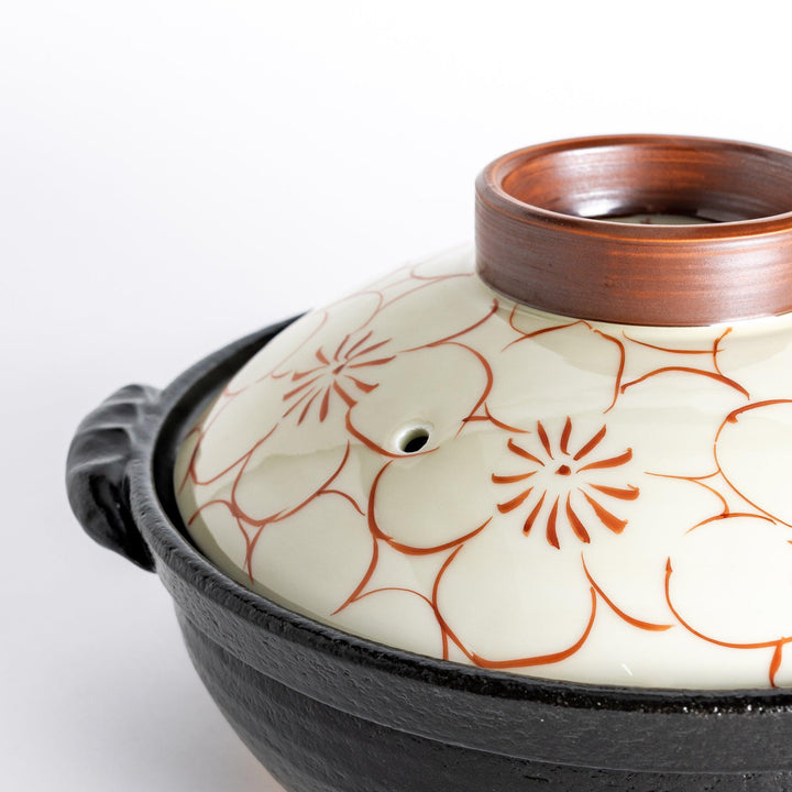 A 8-inch donabe with a vibrant red blossom pattern lid and black pot.