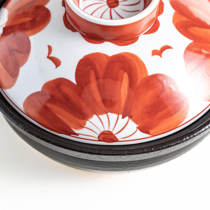 A 8-inch donabe with a vibrant black floral pattern lid and black pot.