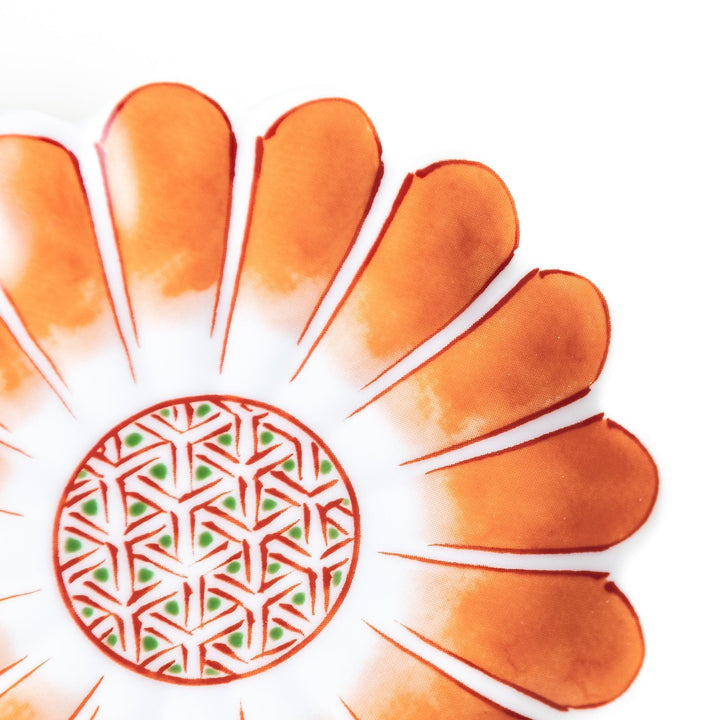 A small, scalloped-edge porcelain dish with orange chrysanthemum petal designs and a geometric center.