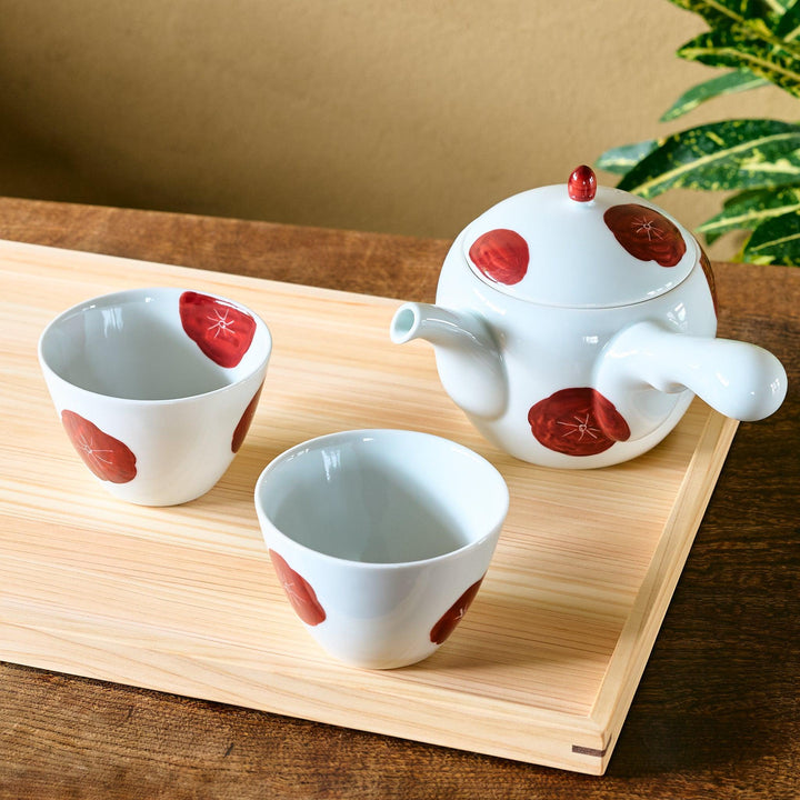 White porcelain Japanese tea set with hand-painted red plum blossoms, featuring one teapot and two matching cups.