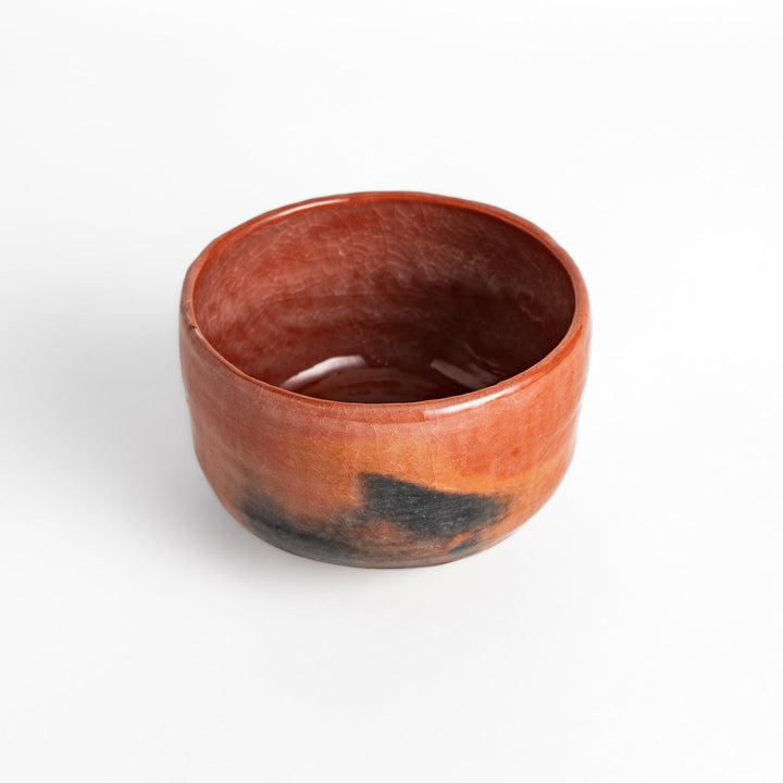 Rustic Raku ware Matcha bowl with a unique textured glaze and a striking black and red design.
