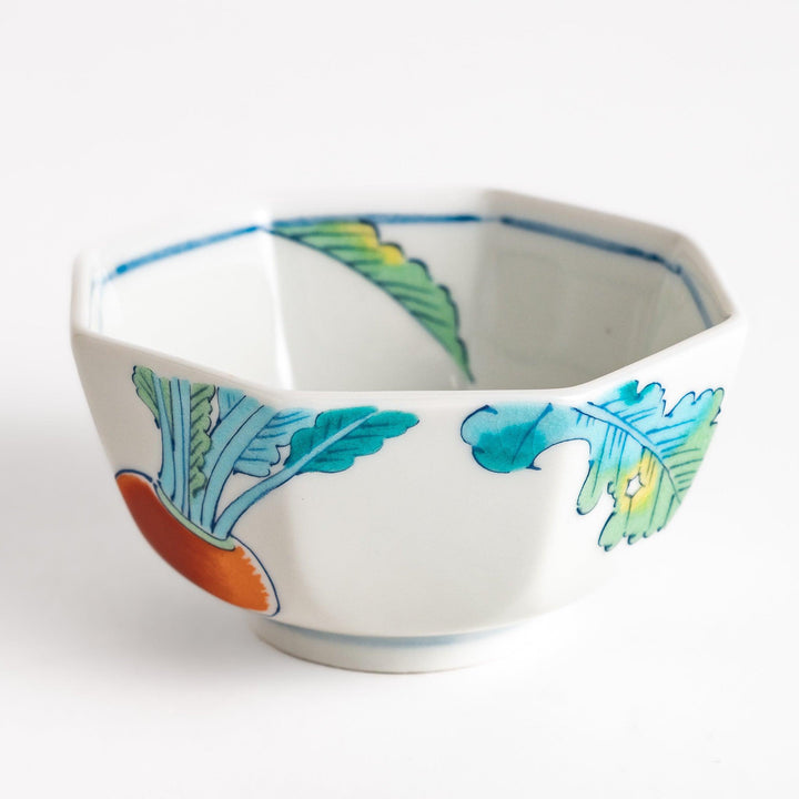 A white porcelain dessert bowl adorned with vibrant illustrations of red turnips and green leaves. Its octagonal shape adds elegance.