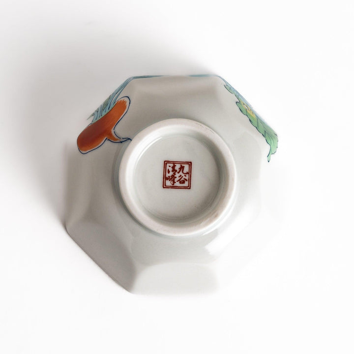 A white porcelain dessert bowl adorned with vibrant illustrations of red turnips and green leaves. Its octagonal shape adds elegance.