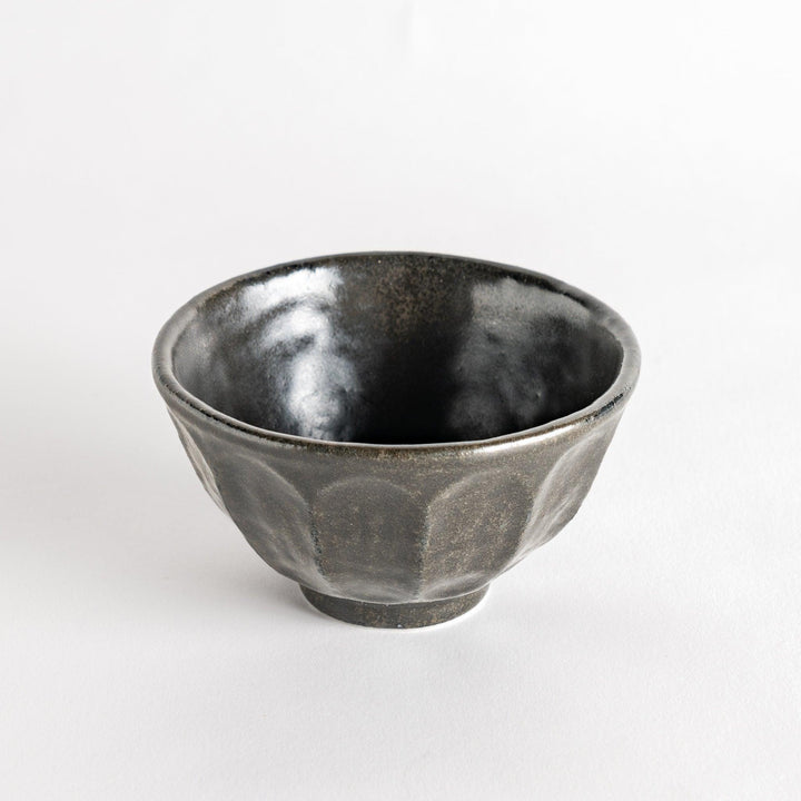 A minimalist ceramic mug with a textured, faceted finish. Available in black or white.