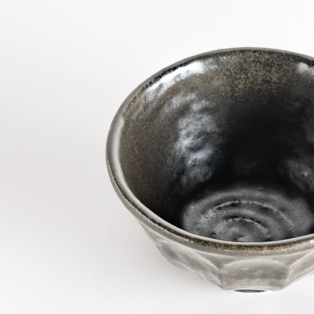 A minimalist ceramic mug with a textured, faceted finish. Available in black or white.