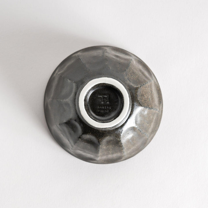 A minimalist ceramic mug with a textured, faceted finish. Available in black or white.