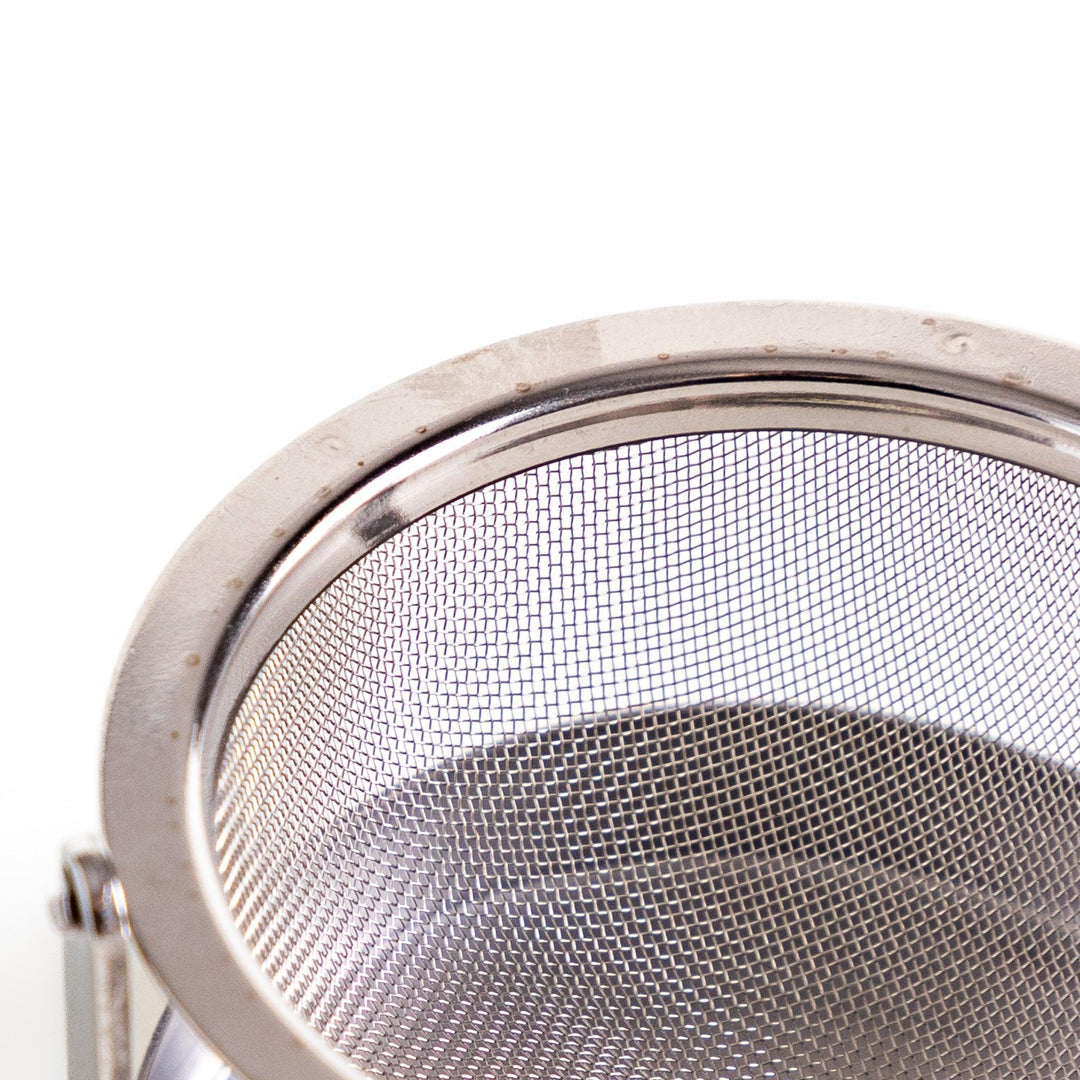 Stainless steel rotating tea strainer with fine mesh and drip tray, designed for effortless loose-leaf tea brewing and easy cleanup.