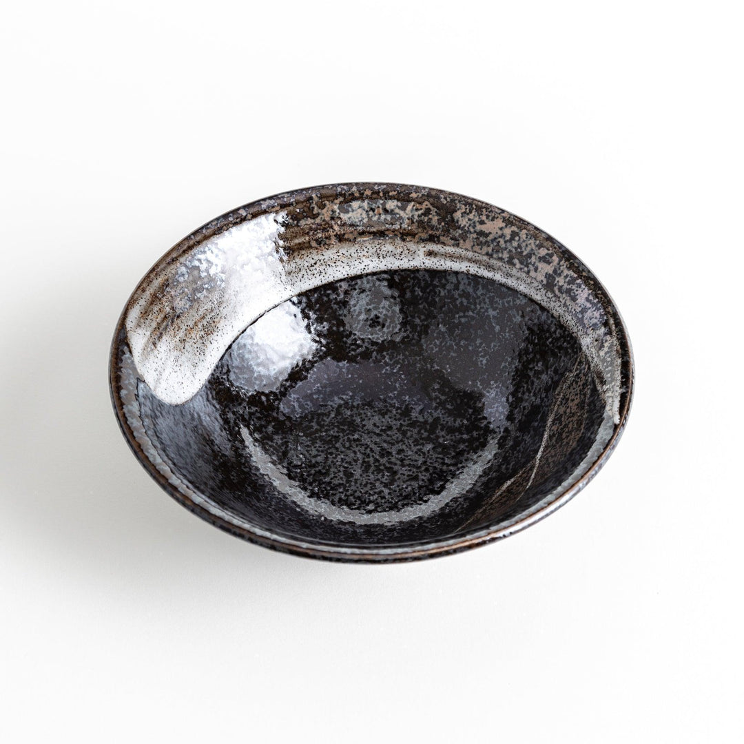 A deep ceramic bowl with a glossy black glaze and irregular brown and speckles.