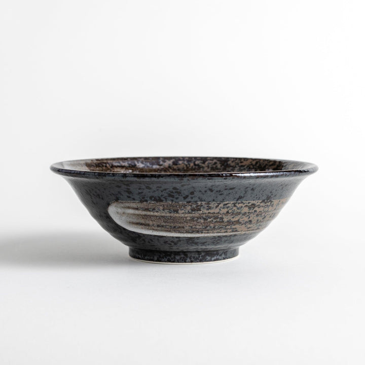 A deep ceramic bowl with a glossy black glaze and irregular brown and speckles.